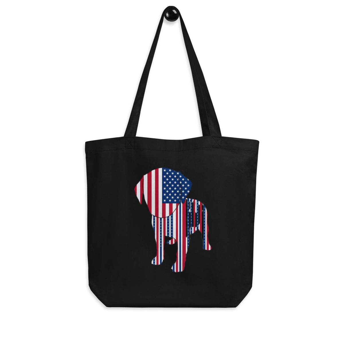 Black 'patriot pup' canvas tote bag hanging on a hook, dog silhouette filled with an American flag pattern, cozy bluesky