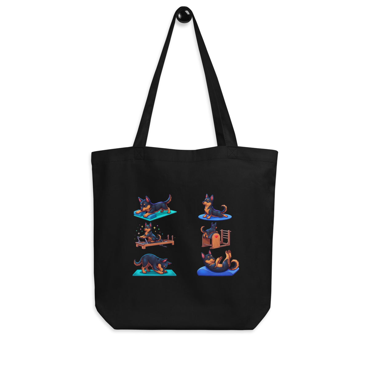 Black 'pilates pups' organic canvas tote bag hanging on a hook, dogs doing pilates on different equipment, cozy bluesky