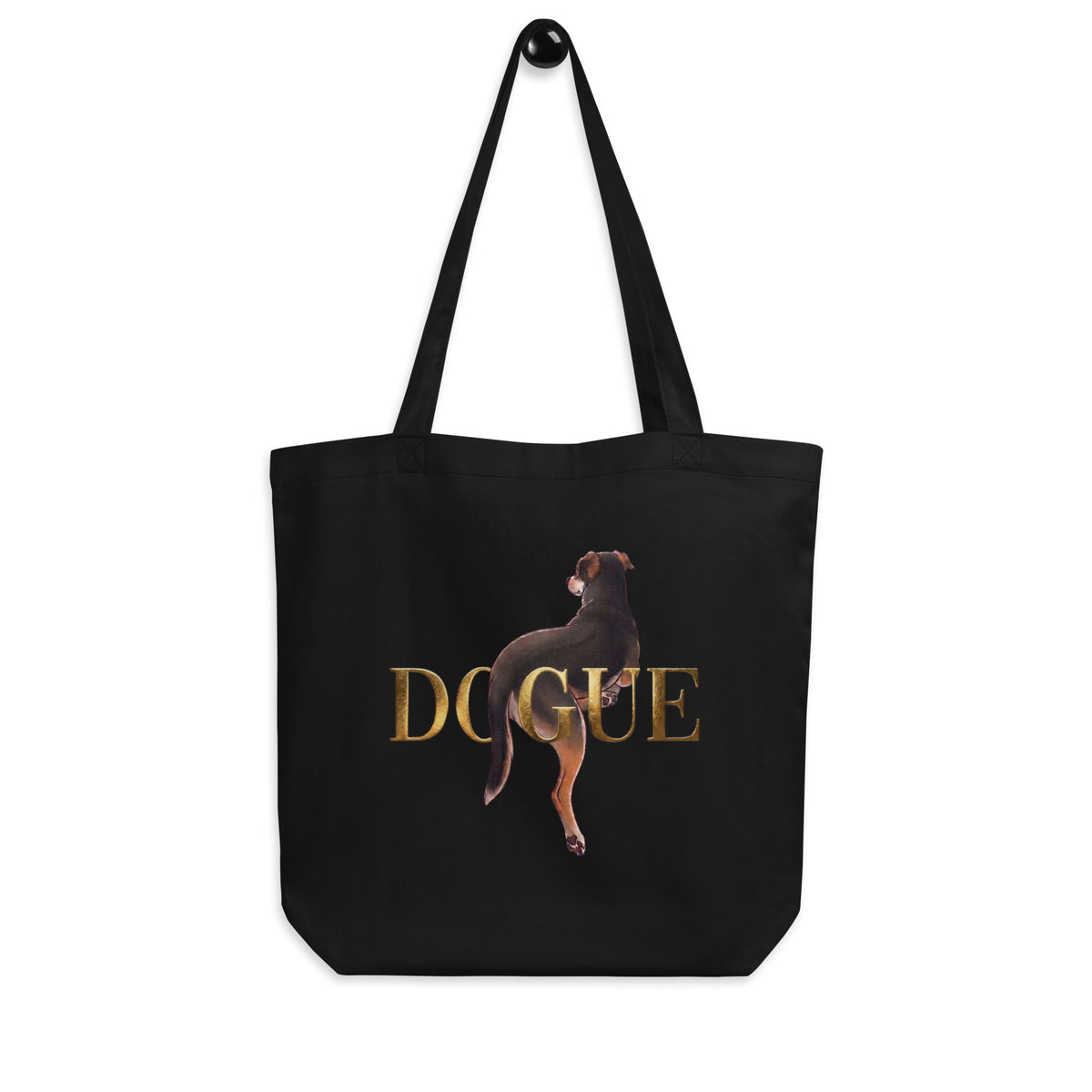 Black 'dogue' organic canvas tote bag hanging on a hook, dog posing over gold DOGUE lettering, cozy bluesky