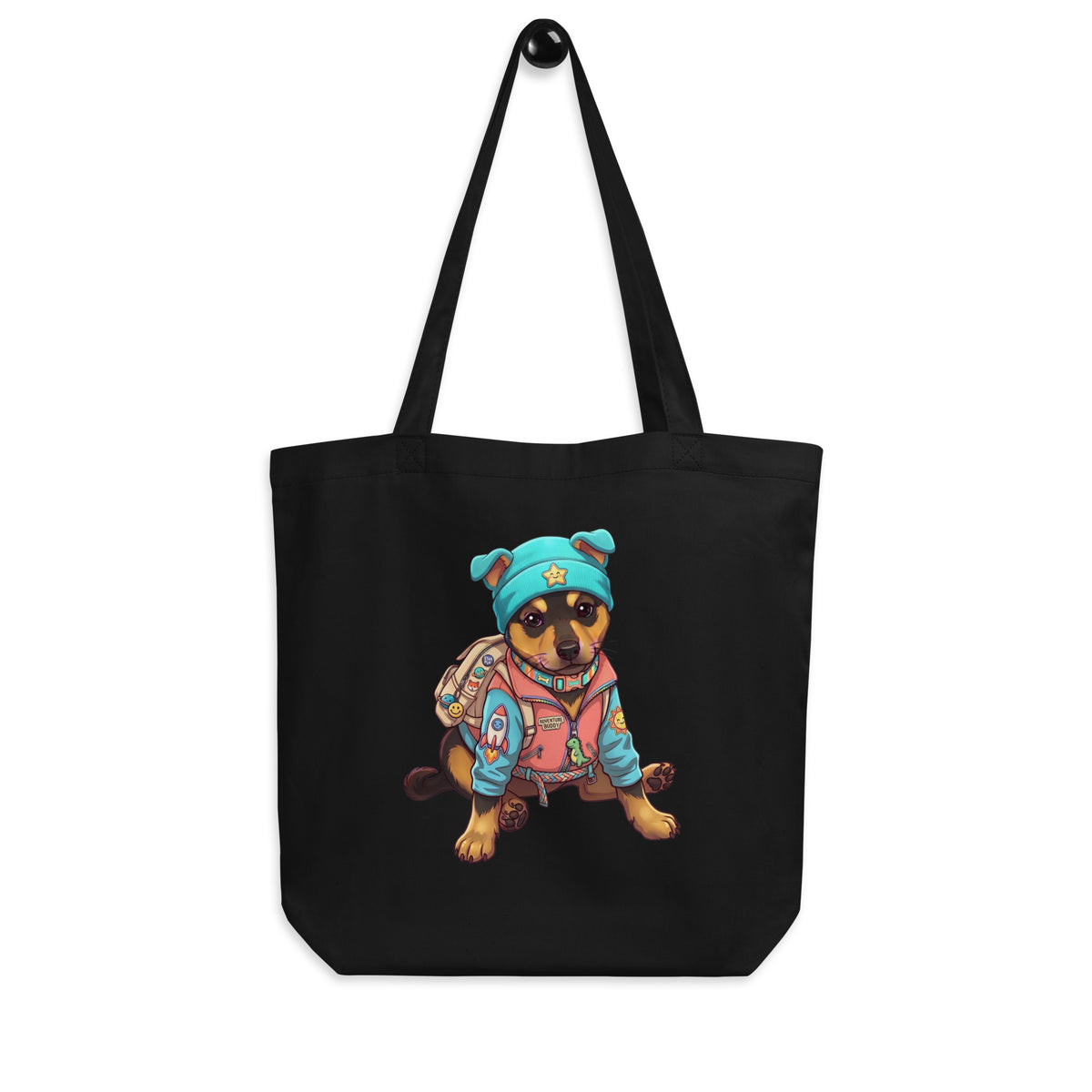 Black 'adventure puppy' canvas tote bag on a hook, dog in a teal star beanie with a backpack and pink jacket, cozy bluesky