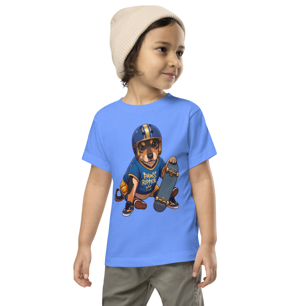 Child in a beanie wearing a heather columbia blue 'skater MVP' toddler t-shirt, dog in a helmet with a skateboard